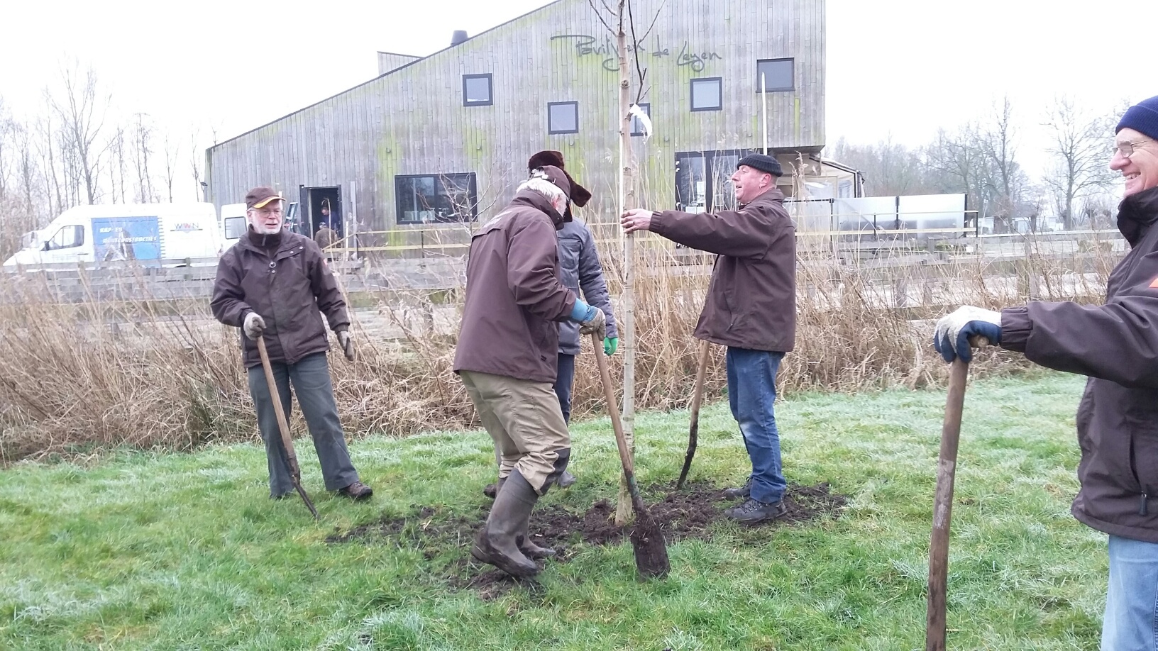 Pier Hager van Paviljoen de Leyen en onze vrijwilligers planten gezamenlijk een aantal walnotenbomen in het nieuwe plukbos.